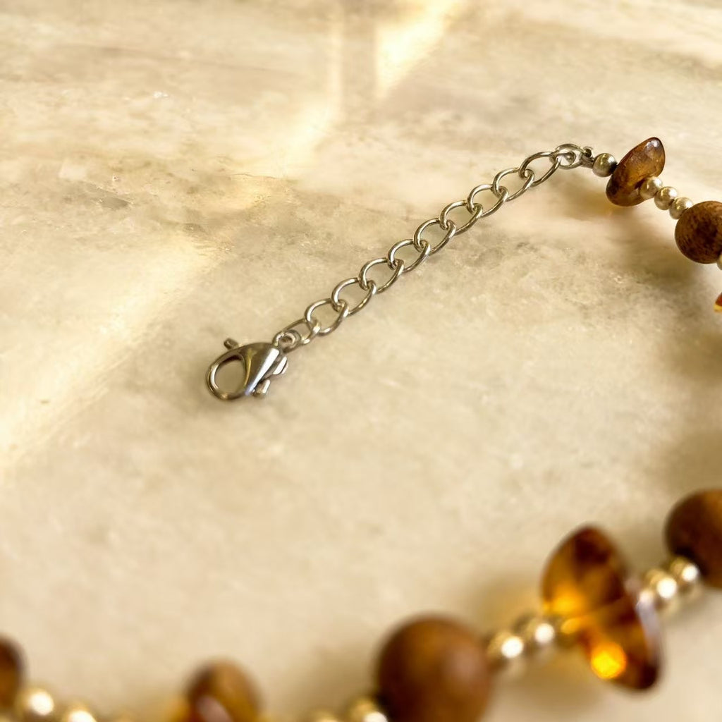 A delicate harmony of natural agarwood and warm amber-inspired stone accents.